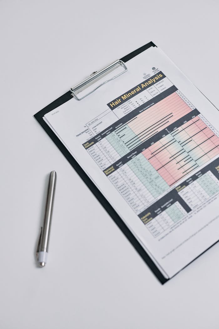 A hair mineral analysis report displayed on a clipboard photographed from above, with a pen nearby.